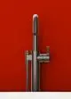 Freistehender Waschbeckenarmatur von Ideal Standard in Magnetic Grey mit schlanker Bauform und Handbedienung, montiert vor roter Wand.